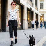 Woman walking a dog on a city street with buildings and people in the background