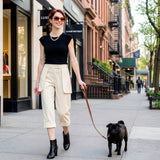 Woman walking a black dog on a leash in an urban setting